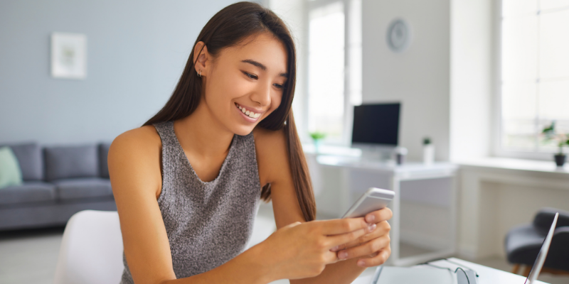 Young woman looking at her phone with a happy expression